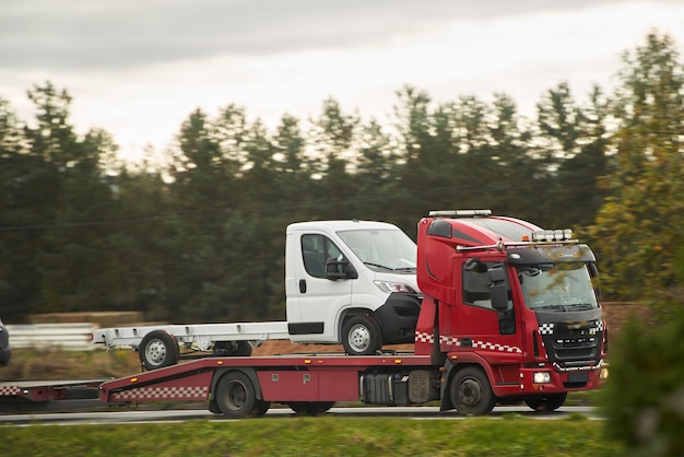 Car breakdown and towing A tow truck with a broken car on a speedway road Towtruck transporting a car on the highway Car service transportation concept