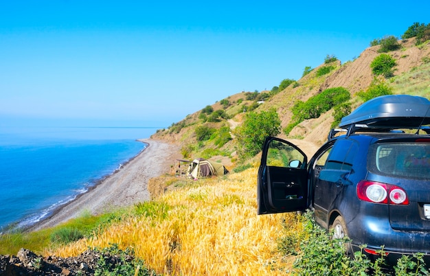 Foto l'auto vicino al mare e tenda camper.