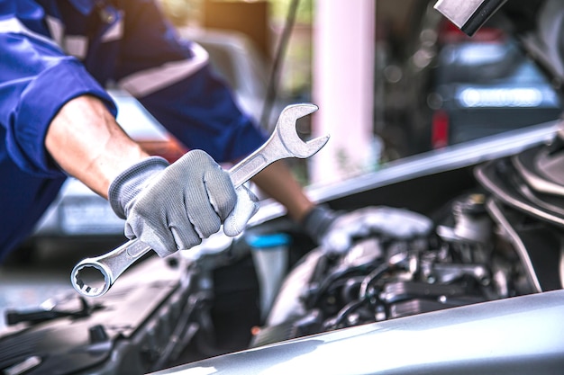 Photo car care maintenance and servicing closeup hand technician auto mechanic using the wrench to repairing change spare part car engine problem and car insurance service support