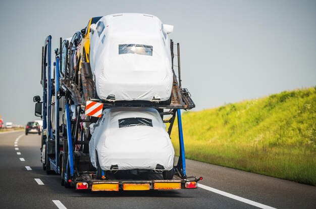 Foto carrier trailer pieno di veicoli che guidano lungo l'autostrada car hauler semi truck veicolo di trasporto