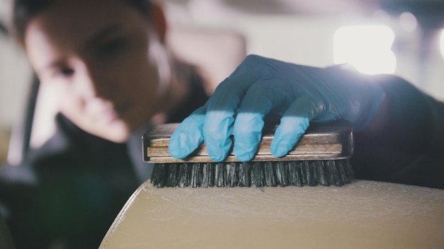 Car cleaning  attractive young woman is washing armchair of a luxury vehicle with a brush