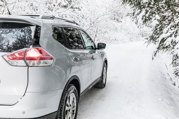 Foto primo piano di auto su una strada invernale nella foresta innevata paesaggio invernale con auto sulla strada e alberi coperti di neve