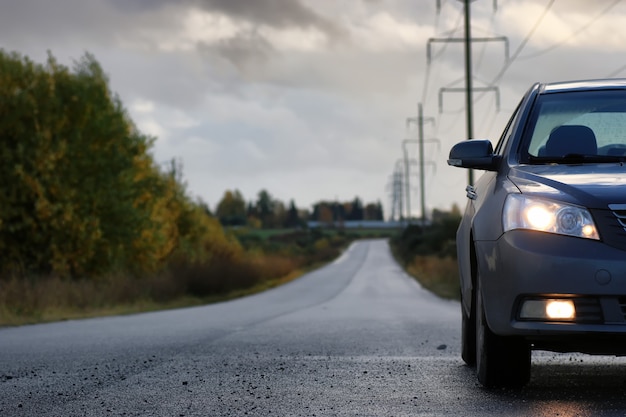 Car on country road lane in rainy autumn day