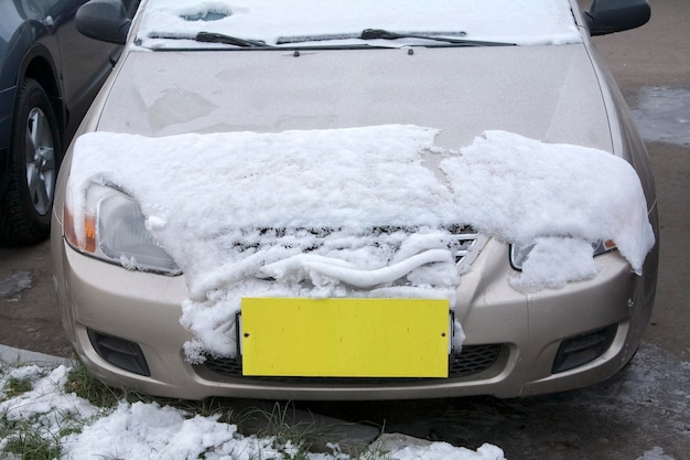 番号の代わりに黄色のラベルが付いた雪で覆われた車