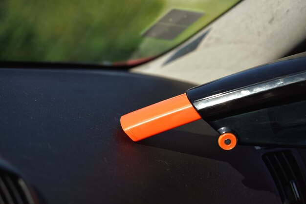 Car dashboard cleaned from dust with small orange portable vacuum cleaner.