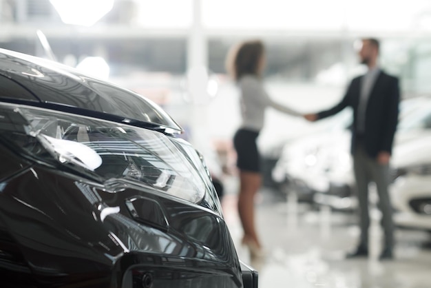 Photo car dealer and client shaking hands in showroom
