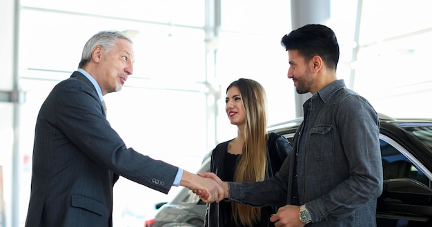 Car dealer giving a handshake to a young couple