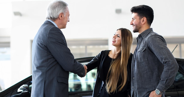 Car dealer giving a handshake to a young couple