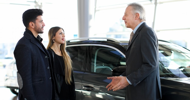 Car dealer showing a car to a couple