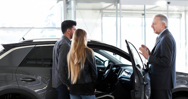 Car dealer showing a car to a couple