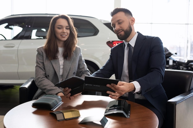 A car dealership employee helps to choose interior trim materials for a new car