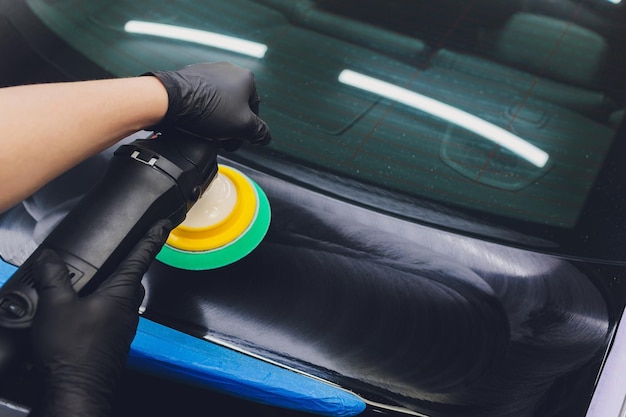 Photo car detailing hands with orbital polisher in auto repair shop selective focus