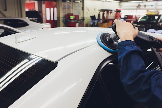 Photo car detailing hands with orbital polisher in auto repair shop selective focus