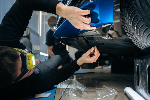 L'uomo dei dettagli dell'auto applica un rivestimento protettivo nano all'auto nel servizio di dettagli dell'auto