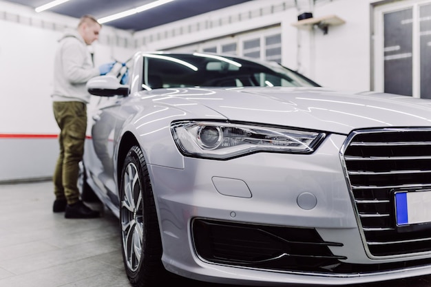 Car detailing - Worker with orbital polisher in auto repair shop. Selective focus.