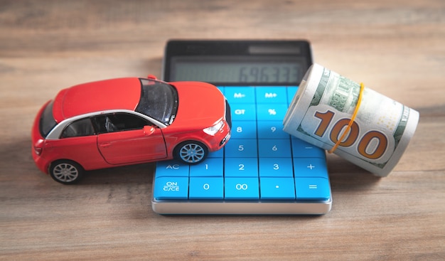 Car, dollar banknotes, calculator on the desk.