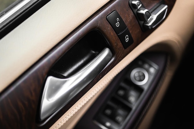 Car door handle inside luxury car interior with leather\
background closeup view photo