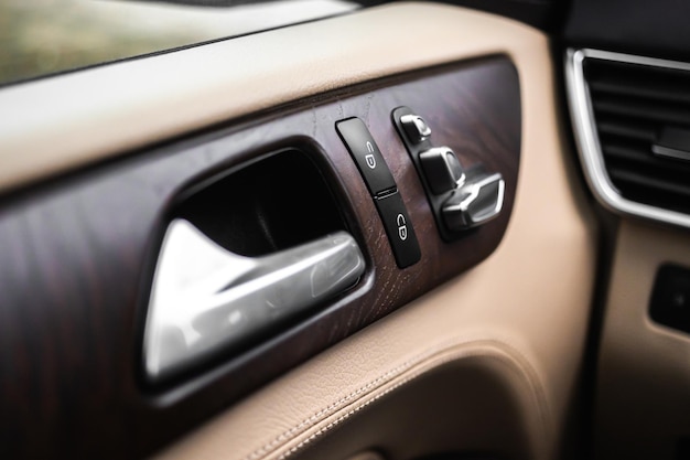 革のインテリアデザインの背景写真と豪華でモダンな車内の車のドアハンドルとロックスイッチ