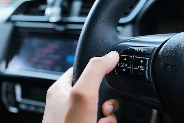 Photo a car driver hand adjusting the sound volume using button on streering wheels