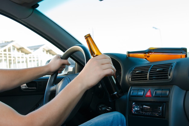 Car driver holding a bottle of beer