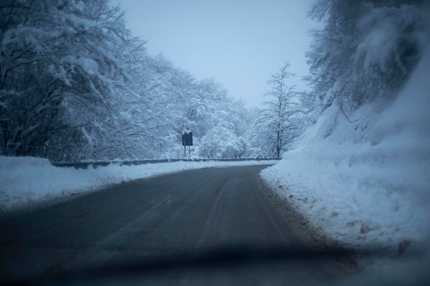 Car drives along a snowy mountain road. Snow covered trees