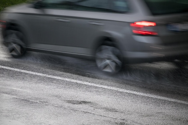 雨の中れた道路で車を運転する