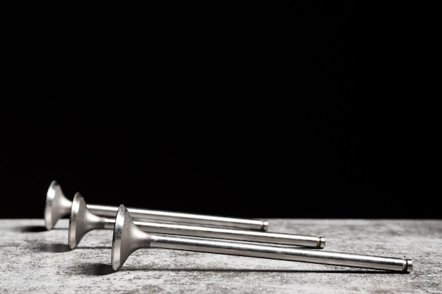 Car engine valves lie on the table on black background Part of an internal combustion engine copy space