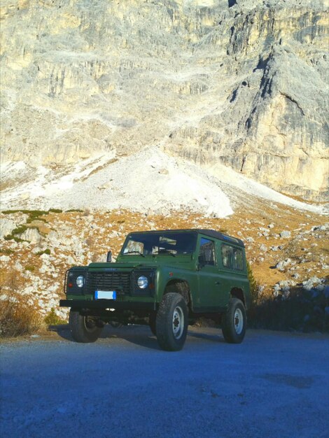 Car on field against rocky mountain