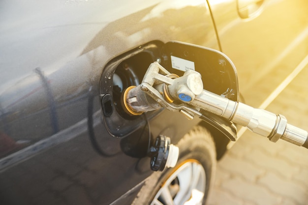 Car fuel up with gas. close up refueling gun in the neck of the tank