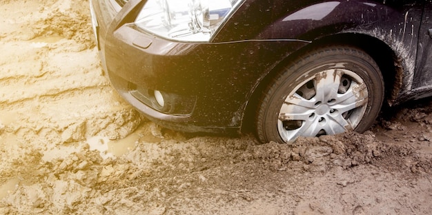 The car got stuck on a dirt road in the mud wheel of a car\
stuck in the mud on the road car on a dir