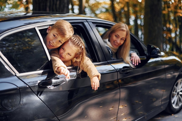 車の中 幸せな家族は一緒に秋の時間に公園にいます