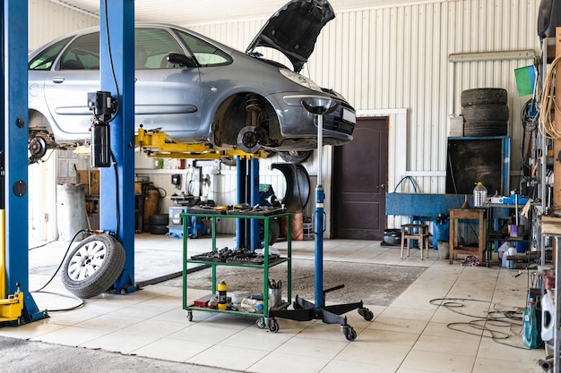 Car is lifted on hydraulic lift in car workshop