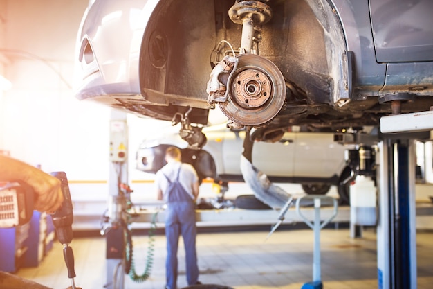 The car is lifted for repair on a lift in a car service station