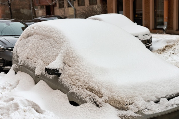Машина зимой завалена снегом на улице города
