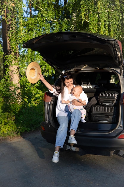 Car journey Travel with a child by car Mother and daughter sit in a car with an open trunk