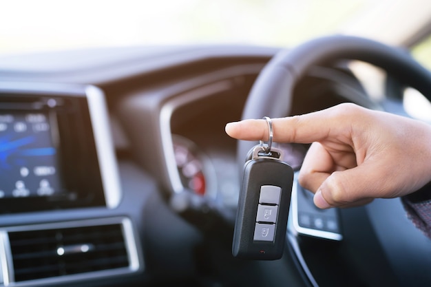 Car key, businessman handing over gives the car key to the other man on car background.