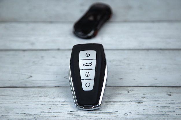 車の鍵は黒で,金属の ⁇ 入と自動ボタンが白い木の背景にあります.