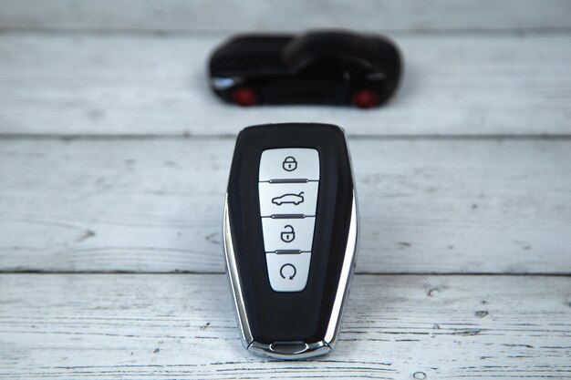 The car keys are black with metal inserts and automatic buttons on the background of white wood on