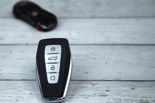 The car keys are black with metal inserts and automatic buttons on the background of white wood on