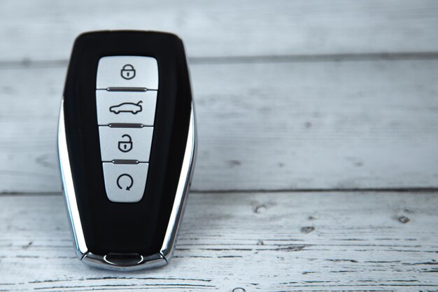 The car keys are black with metal inserts and automatic buttons lying on the side against a white