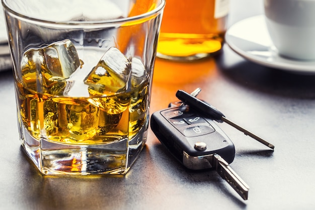 Car keys and glass of alcohol on table in pub or restaurant.