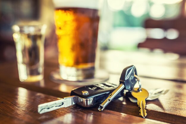 Photo car keys and glass of beer or distillate alcohol on table in pub or restaurant