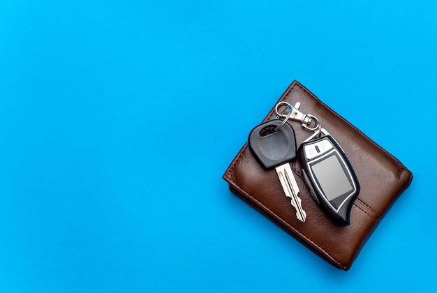 Car keys with wallet on blue background top view