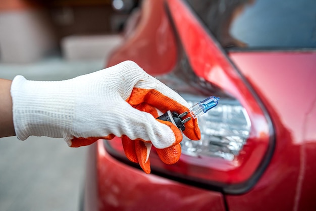 Car lamp in a hand on the background of a car headlight