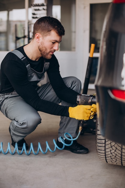 Car mechanic changing wheels in car