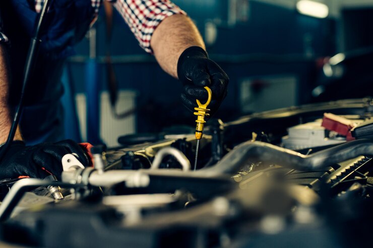 Car mechanic checking oil level in a mechanical workshop