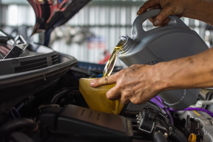 Photo car mechanic fills a fresh lubricant engine oil at car garage for maintenance a car