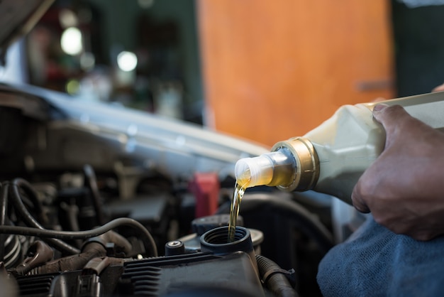 Car mechanic fills a fresh lubricant engine oil