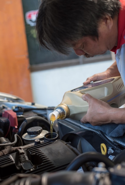 Car mechanic fills a fresh lubricant engine oil