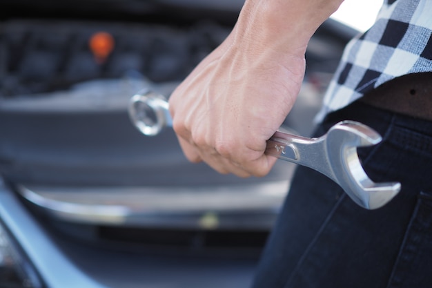 Car mechanic hand with a car repair wrench.